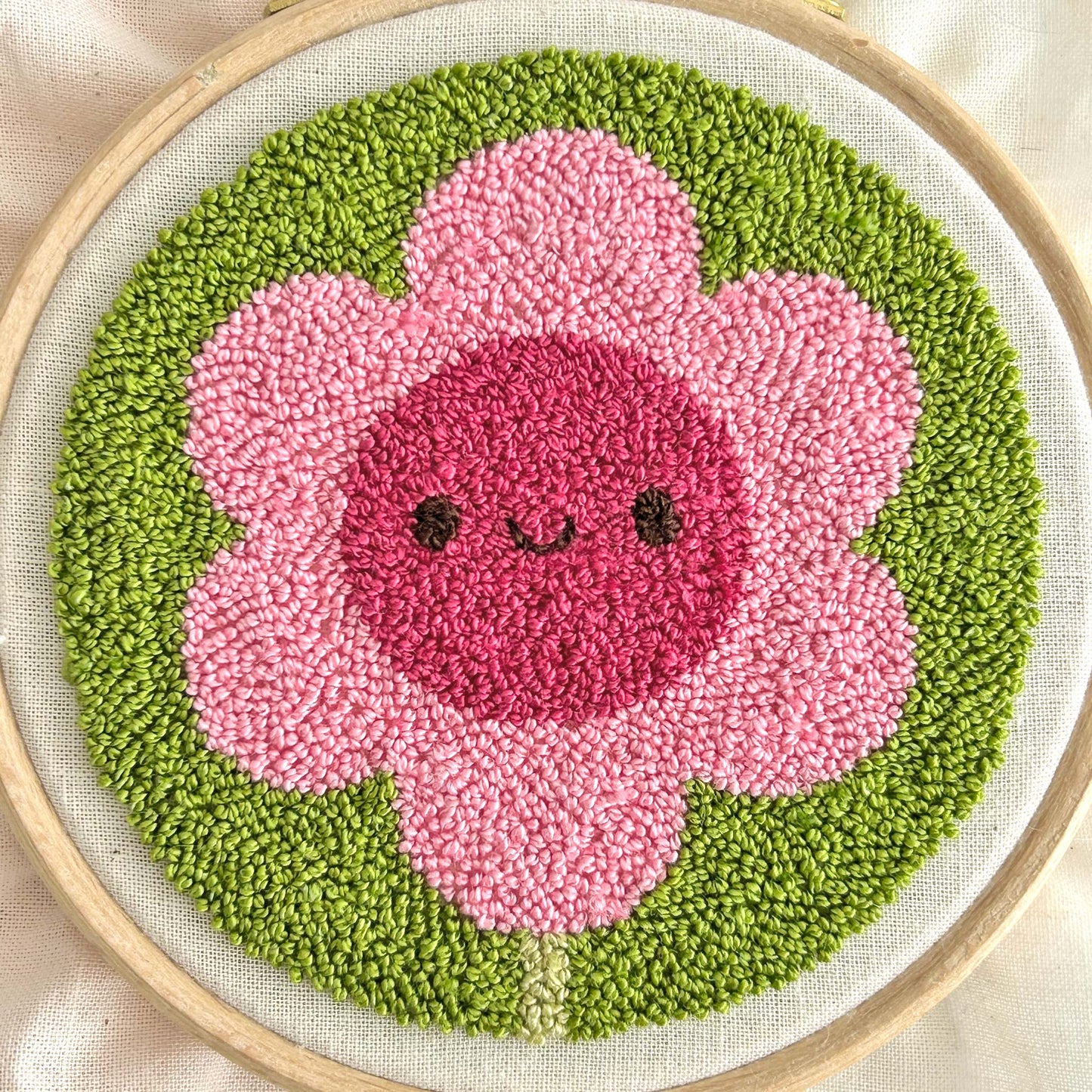 Close-up of finished miniature punch needle flower showing tiny pile stitches and loop texture