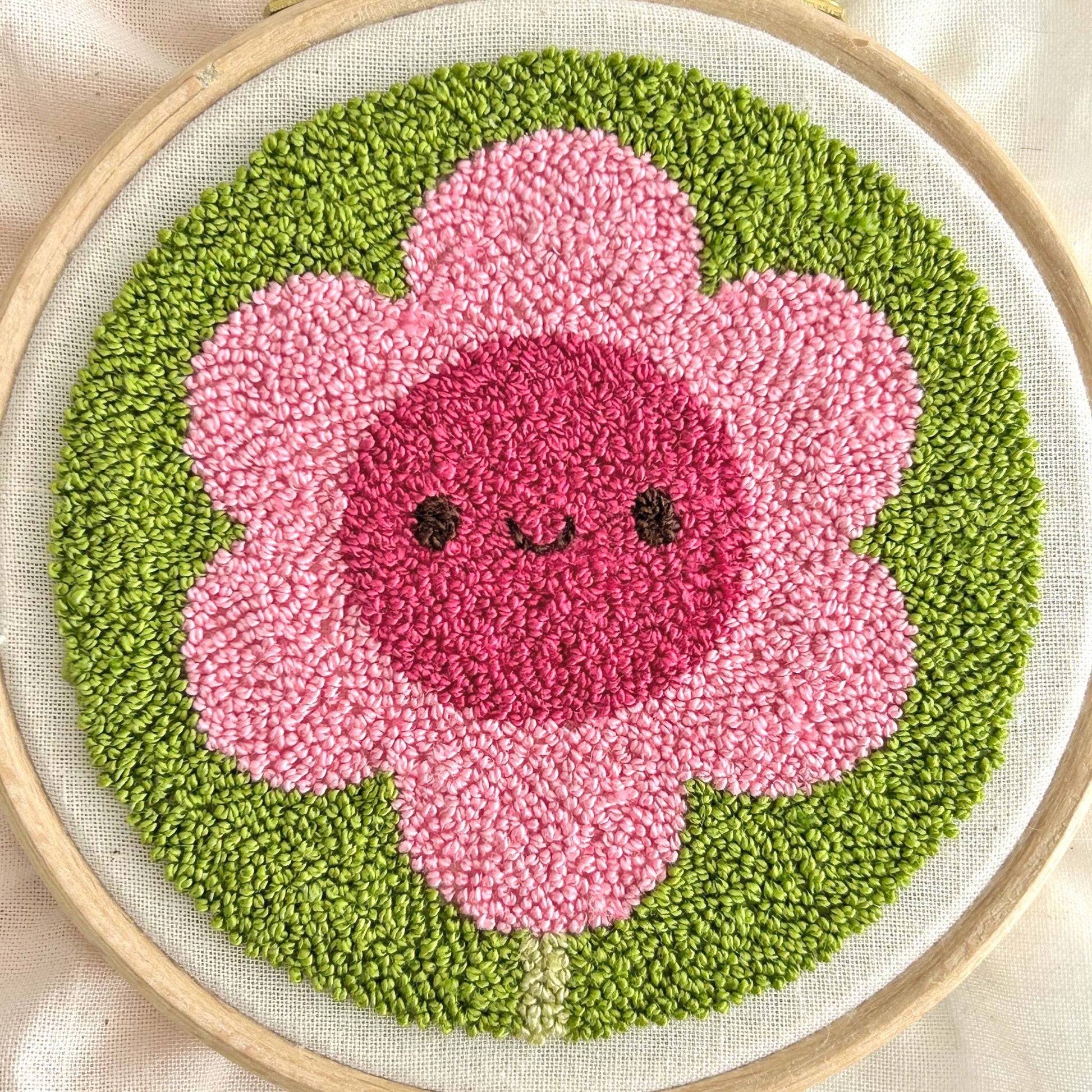 Close-up of finished miniature punch needle flower showing tiny pile stitches and loop texture