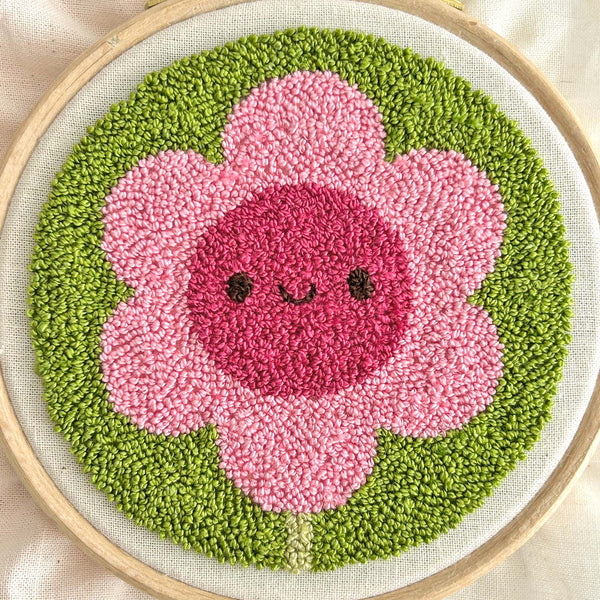 Close-up of finished miniature punch needle flower showing tiny pile stitches and loop texture