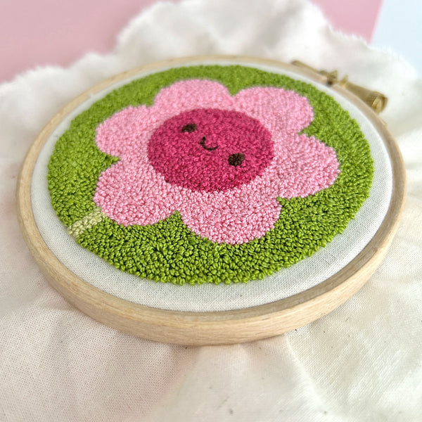 Angled miniature punch needle flower close-up highlighting detailed punch needle loops or pile stitches